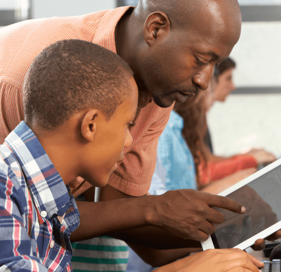 A man and a boy are intently observing a computer screen together, sharing a moment of discovery and learning.