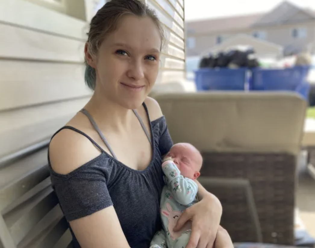 Mom smiling at a camera with a baby on her arms