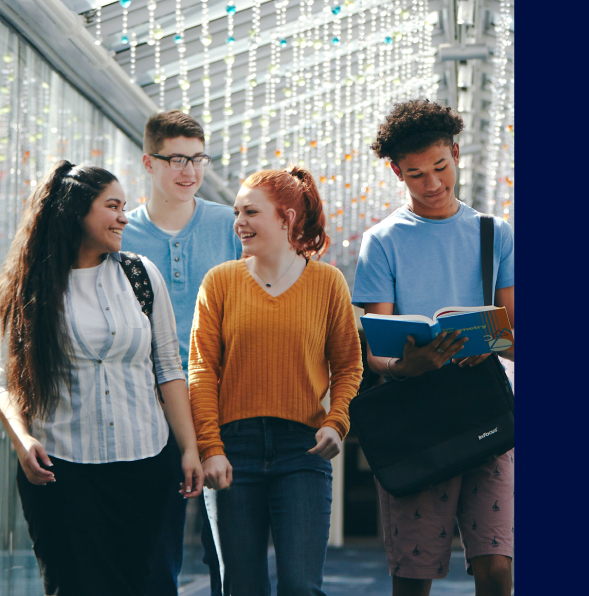 Four young individuals stroll together in a sunny courtyard, enjoying each other's company and the vibrant surroundings.