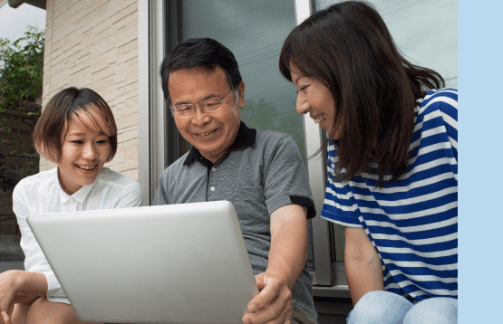 Three individuals gathered around a laptop, engaged in discussion and focused on the screen's content.