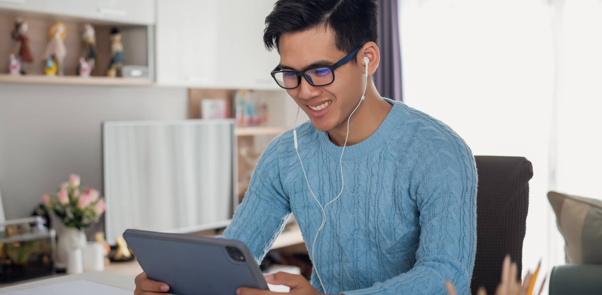 A man wearing glasses is focused on using a tablet computer, showcasing modern technology in action.