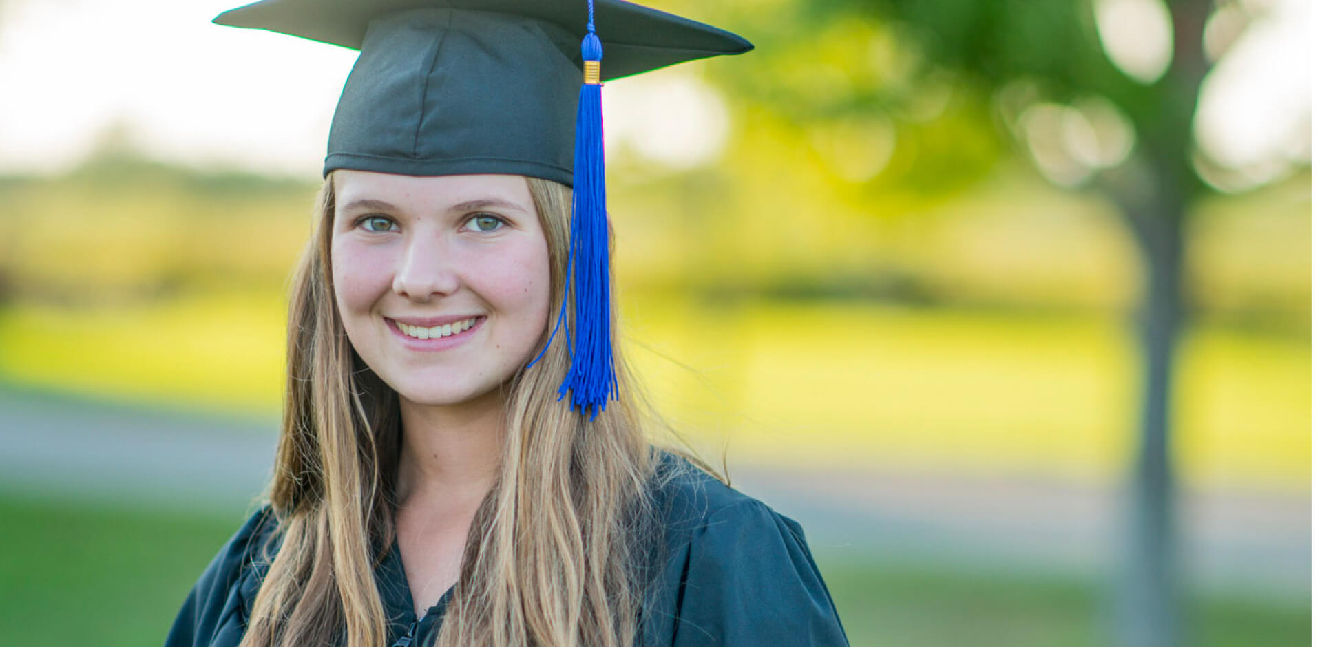 A young woman proudly wearing a graduation cap and gown, celebrating her academic achievement with a joyful expression.