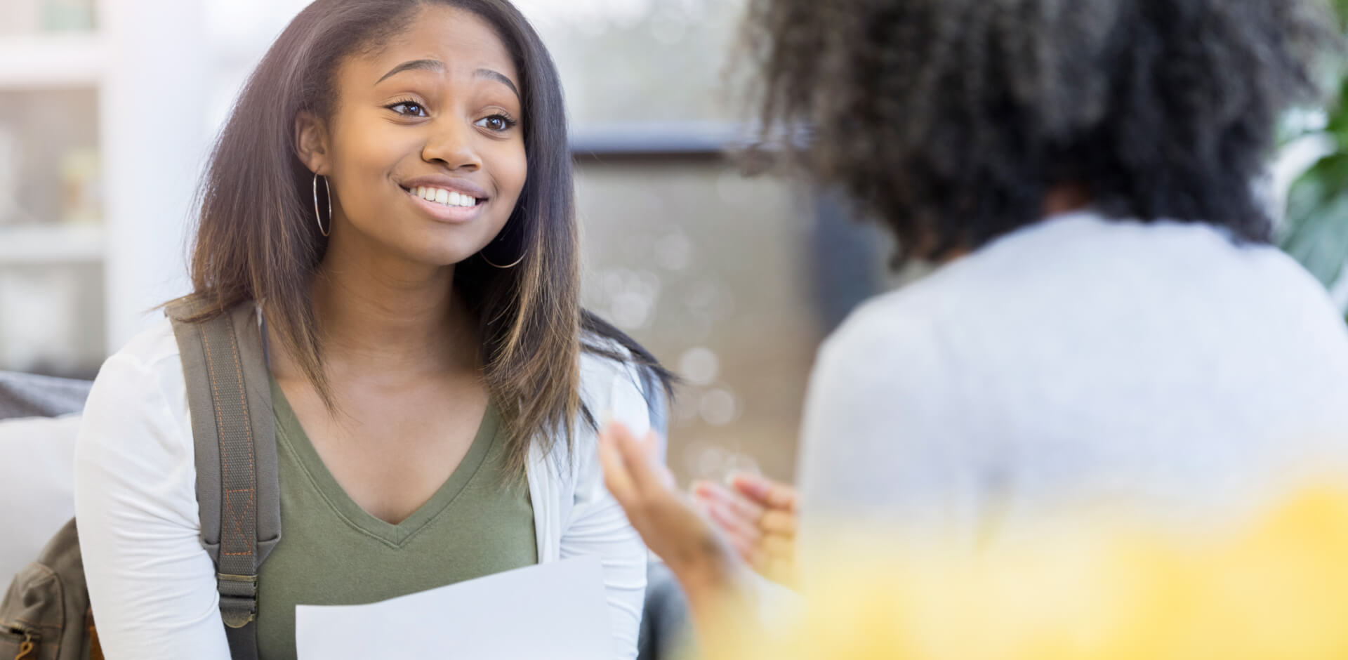 A young woman engages in conversation with another woman, both appearing attentive and engaged in the discussion.