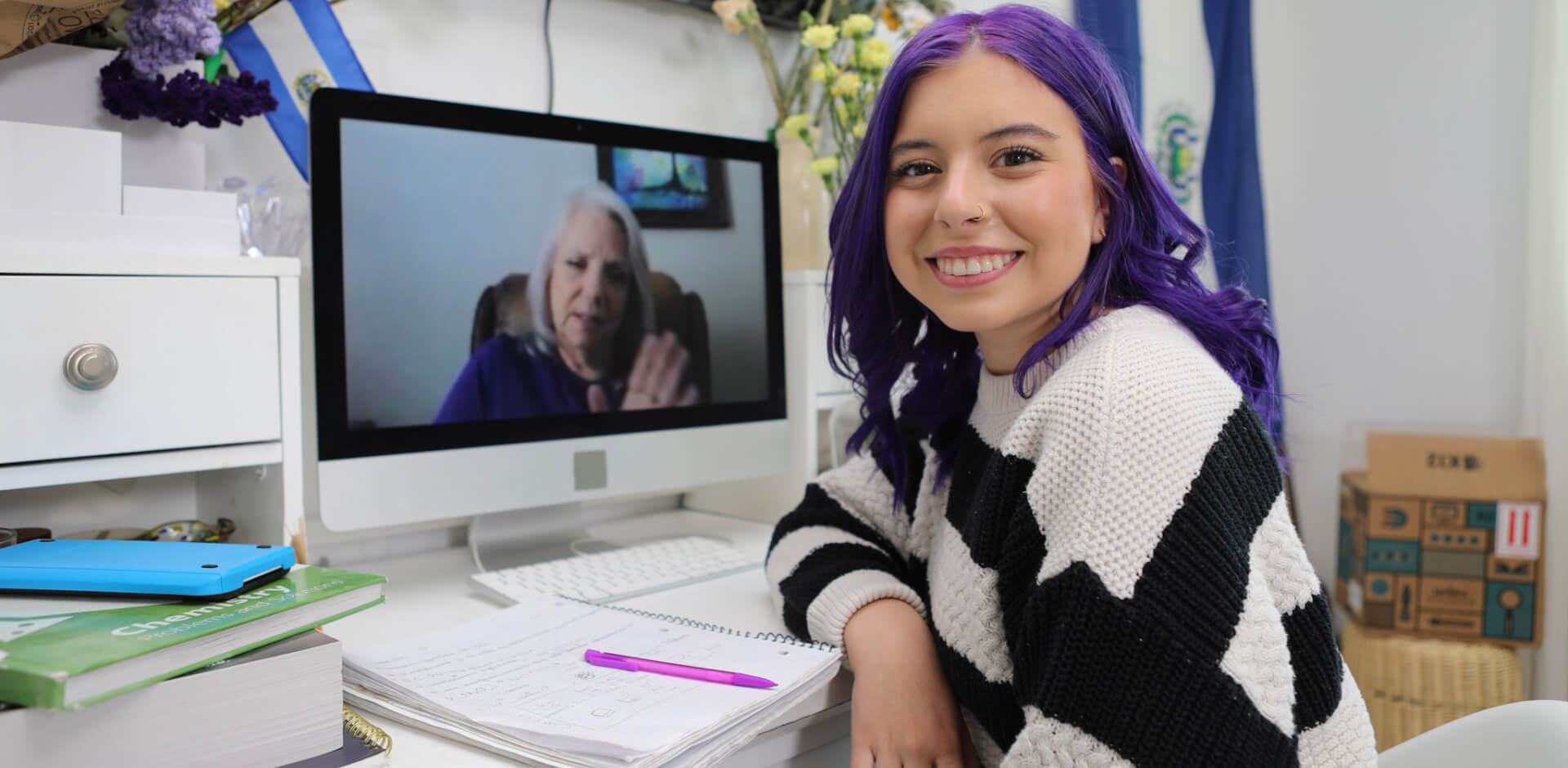A woman with purple hair is seated at a desk, focused on her computer screen, creating a vibrant workspace.