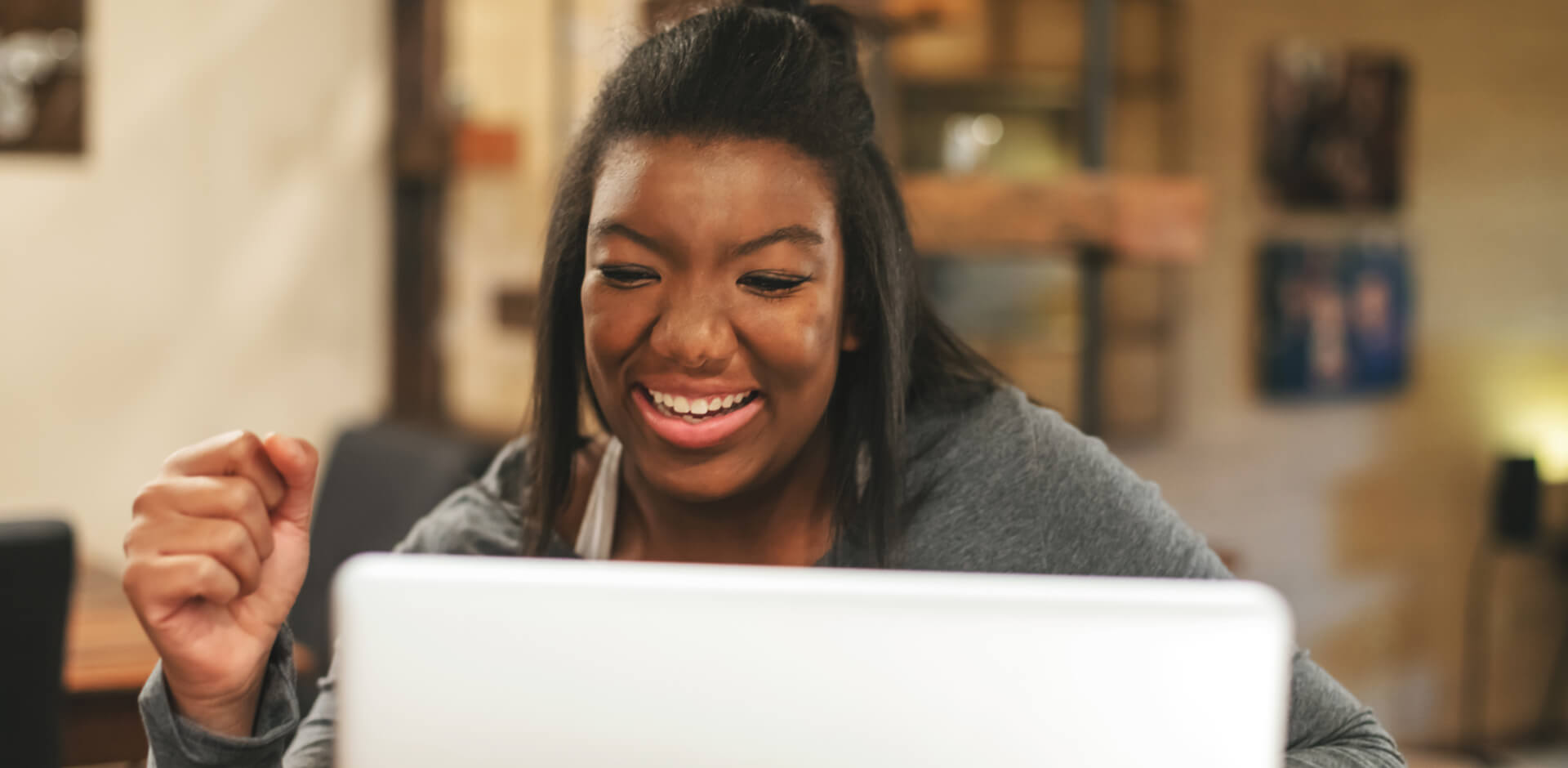 A woman smiles while working on her laptop, showcasing a moment of joy and productivity.