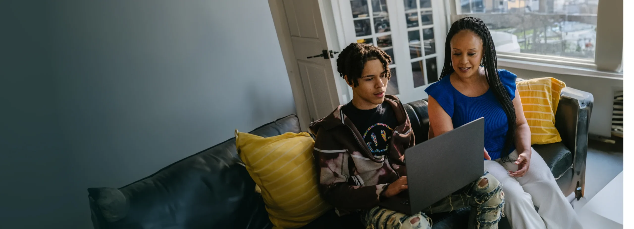 Mother and her son working together with their laptop at home